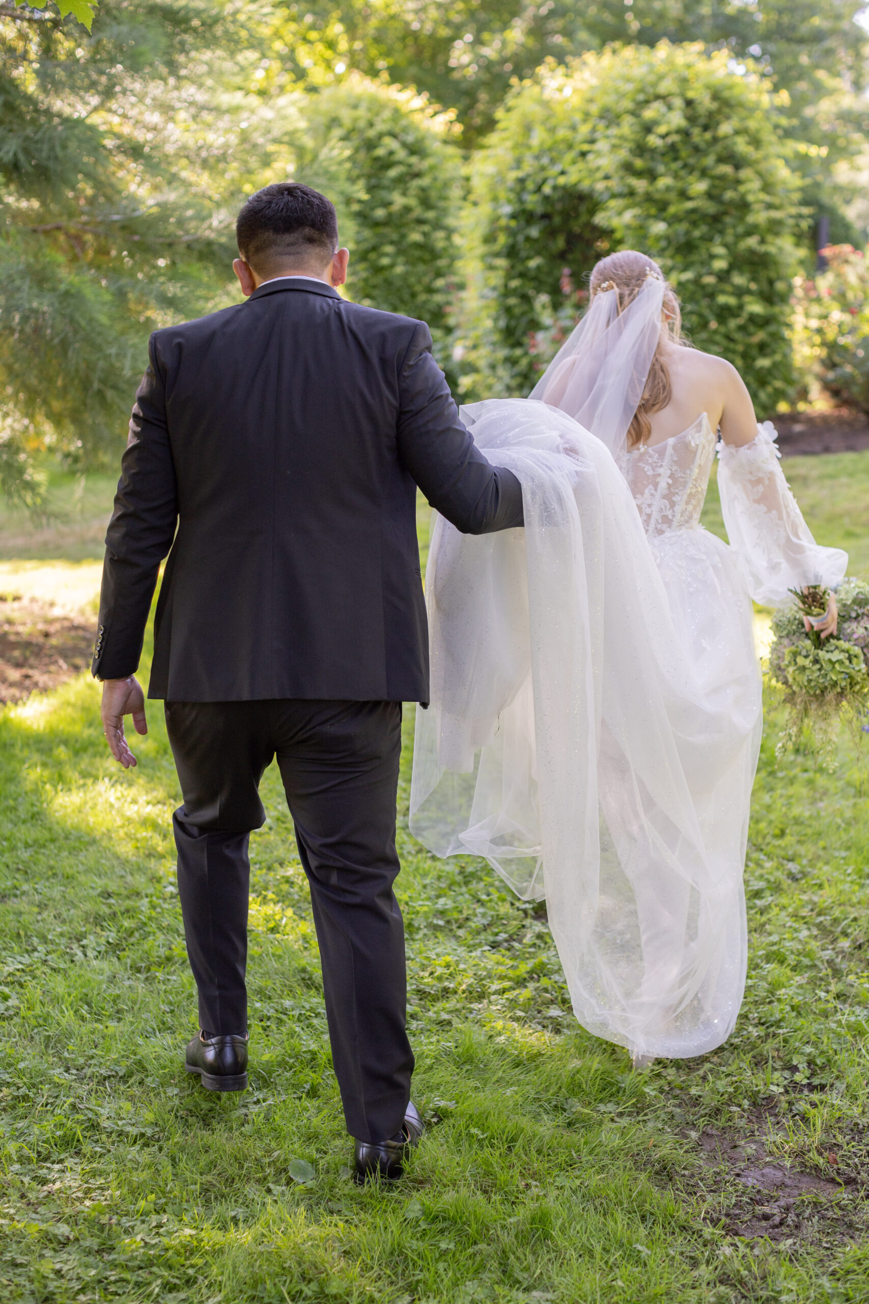groom-holding-brides-dress-while-walking
