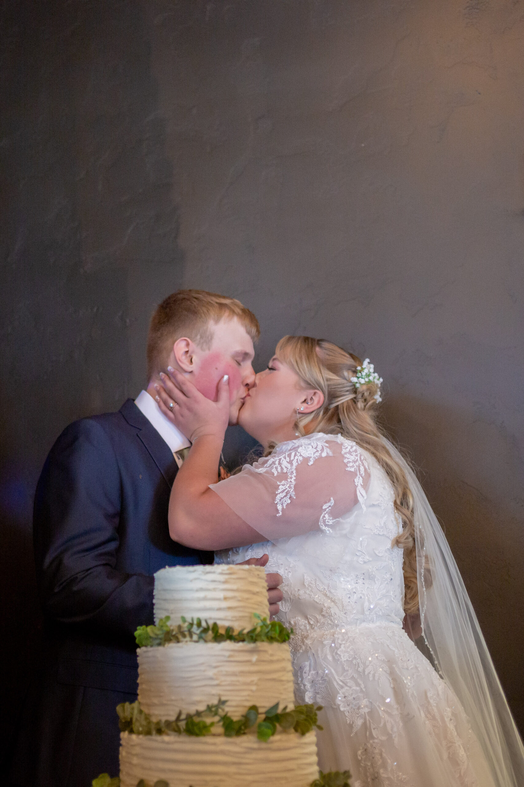 bride and groom kiss after cutting the cake