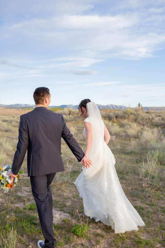 bride-and-groom-walking-through-sagebrush-holding-hands